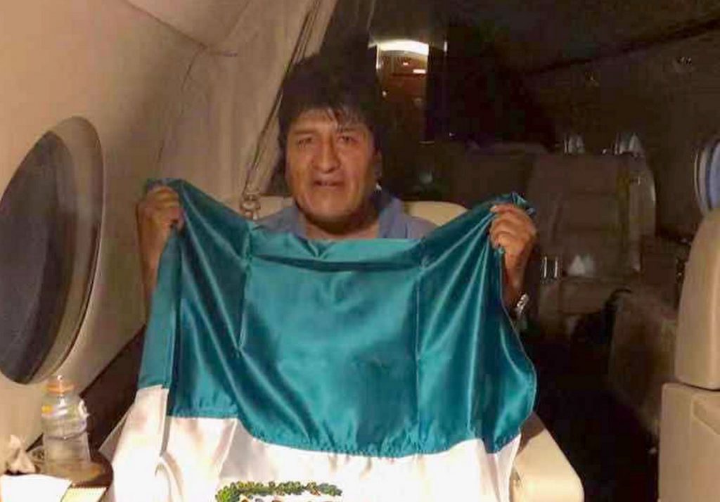 Evo Morales sosteniendo la bandera de México durante su traslado